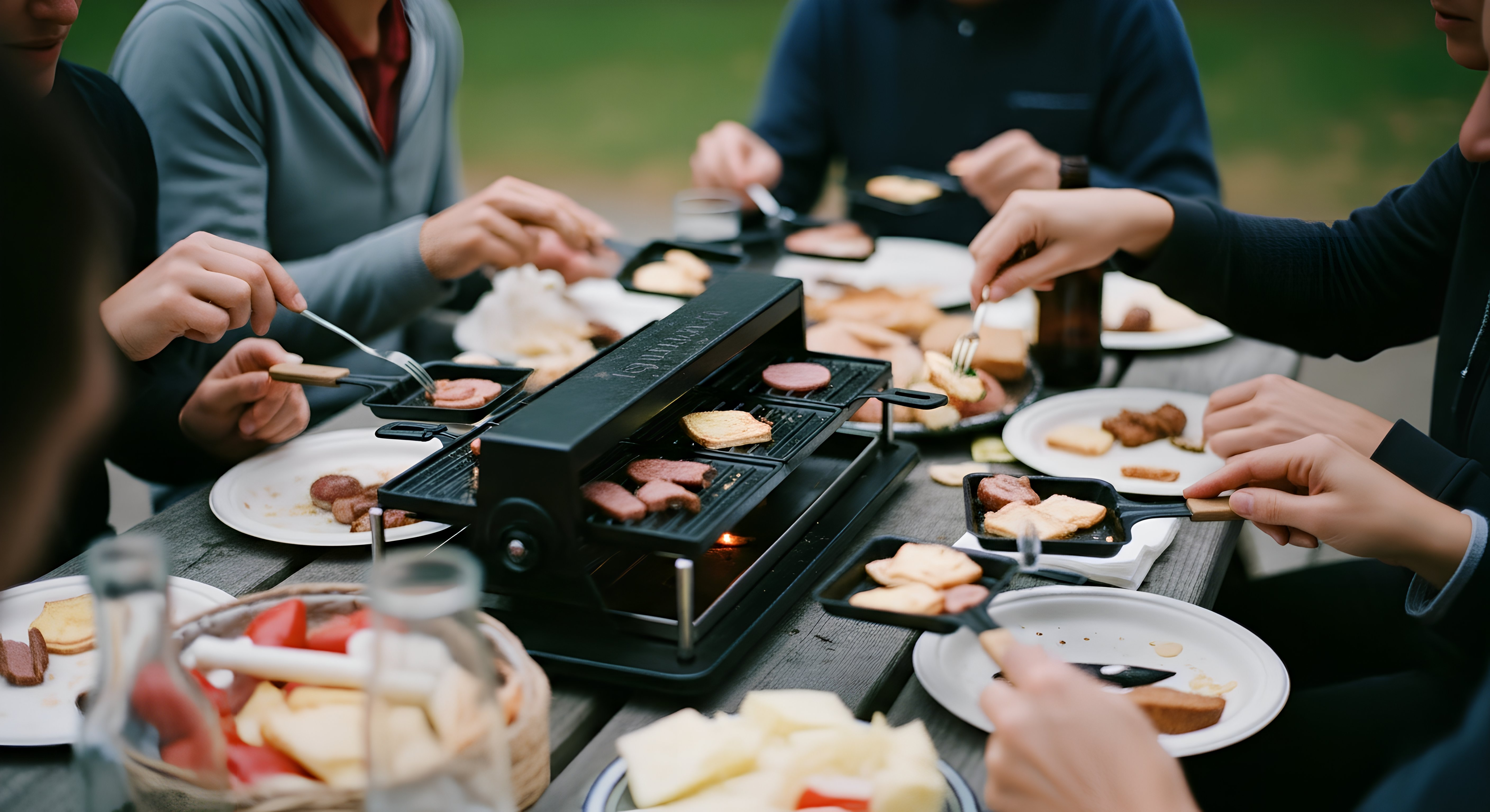 a group of people eating at a campground picnic table using a raclette as an example of RV kitchen appliances